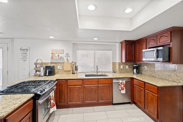 kitchen featuring light stone counters, a textured ceiling, tasteful backsplash, sink, and appliances with stainless steel finishes