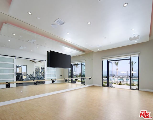 workout area with a barn door and hardwood / wood-style flooring