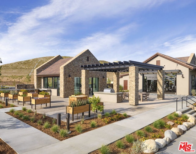 view of community with exterior kitchen, a patio area, an outdoor living space, and a pergola