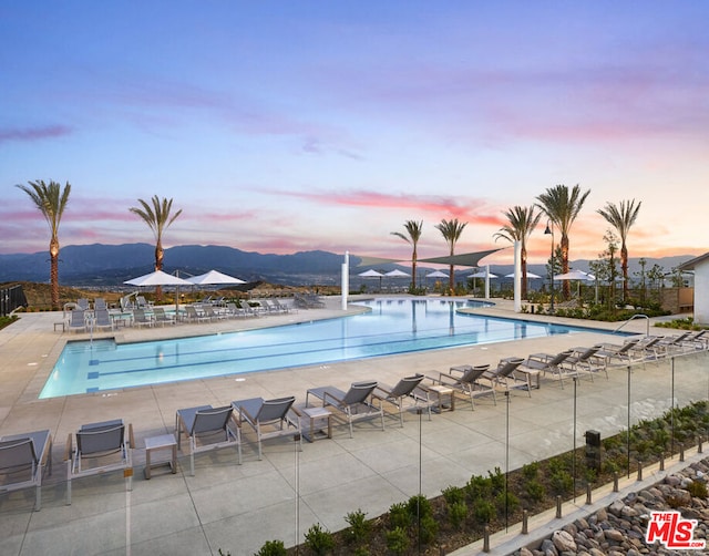 pool at dusk with a mountain view and a patio area