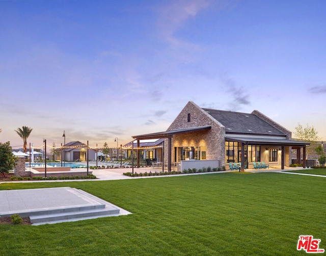 back house at dusk with a yard and a patio