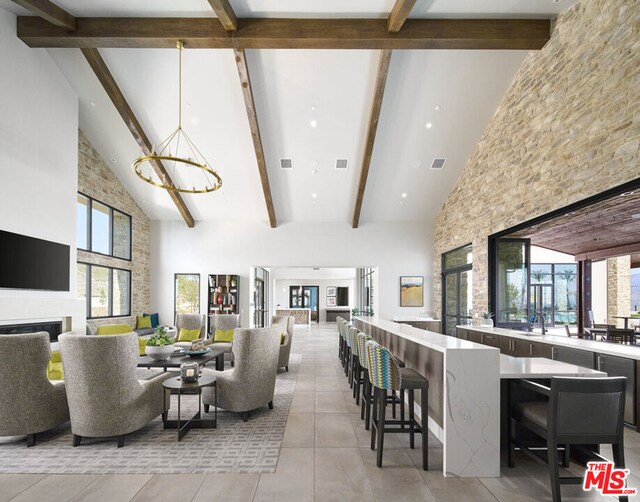 tiled living room with high vaulted ceiling, beam ceiling, sink, and a chandelier