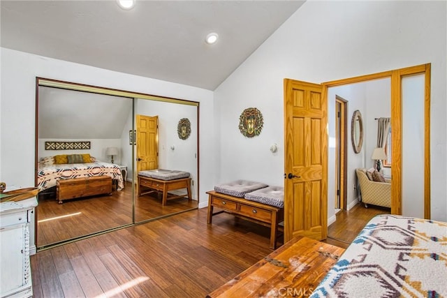 bedroom featuring hardwood / wood-style flooring, lofted ceiling, and a closet