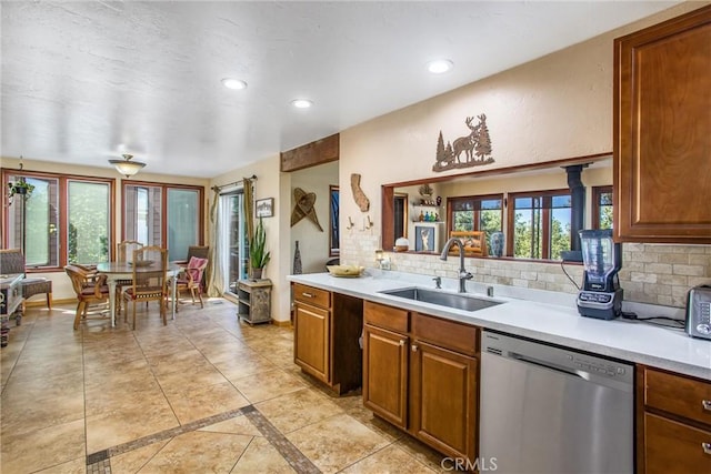 kitchen featuring tasteful backsplash, dishwasher, light tile patterned flooring, and sink