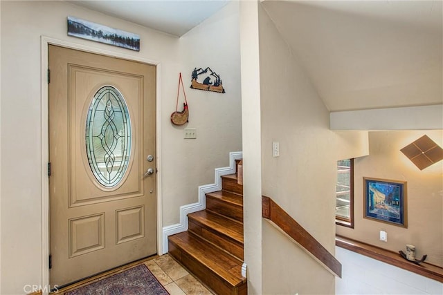 foyer entrance featuring light tile patterned floors and vaulted ceiling