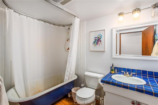 full bathroom with hardwood / wood-style floors, vanity, shower / tub combo, and toilet