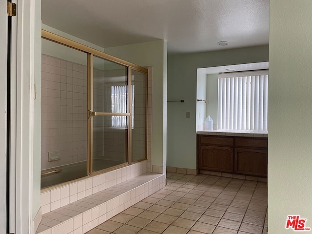 bathroom featuring vanity, a shower with shower door, a textured ceiling, and tile patterned floors