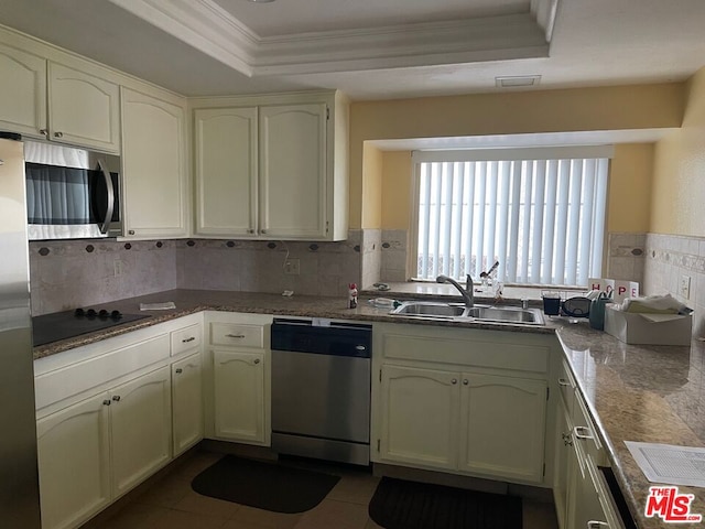 kitchen with appliances with stainless steel finishes, backsplash, a tray ceiling, and sink