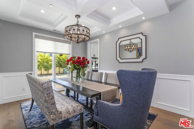 dining space with coffered ceiling, ornamental molding, dark wood-type flooring, and an inviting chandelier