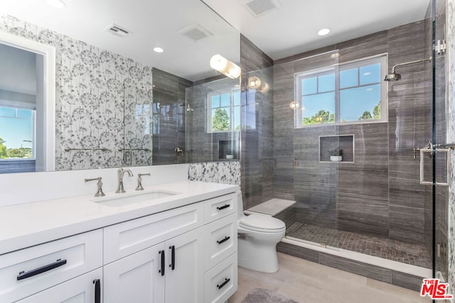 bathroom with vanity, a shower with shower door, and toilet