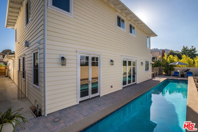 rear view of property with a fenced in pool and a patio area