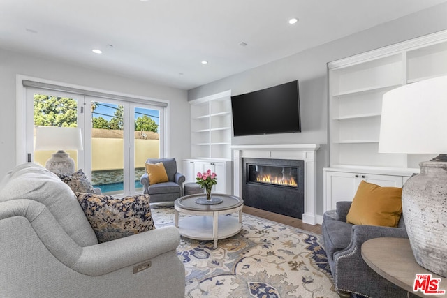 living room featuring built in shelves and light wood-type flooring