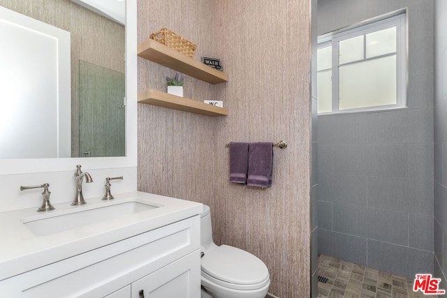 bathroom with vanity, a tile shower, and toilet