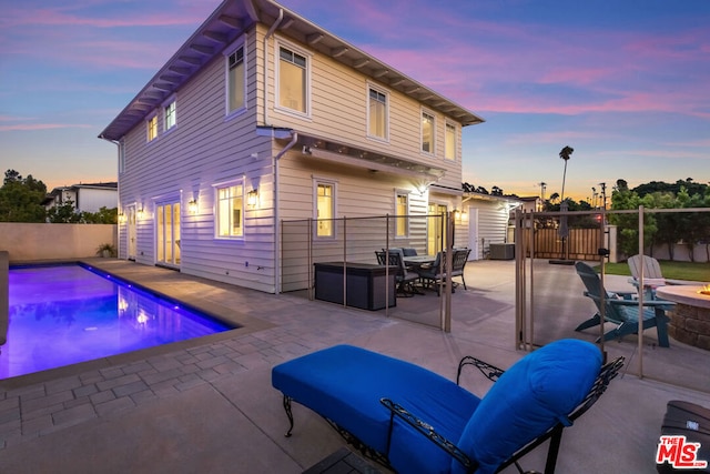 pool at dusk with a patio area and a fire pit