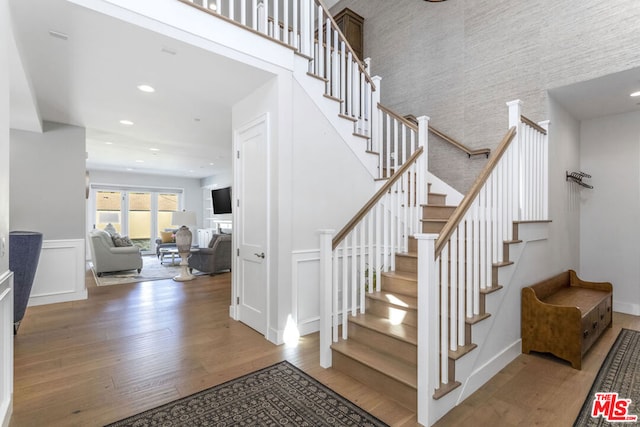 staircase with hardwood / wood-style flooring and a towering ceiling