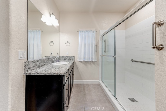 bathroom featuring walk in shower, vanity, tile patterned flooring, and a wealth of natural light