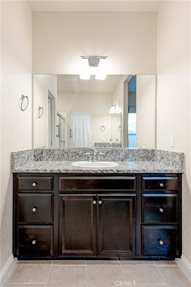 bathroom featuring walk in shower, vanity, and tile patterned floors