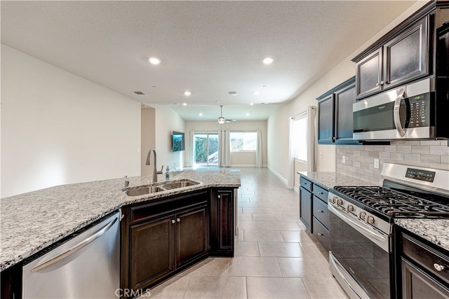 kitchen featuring appliances with stainless steel finishes, light tile patterned flooring, backsplash, light stone countertops, and sink