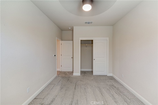 unfurnished bedroom featuring ceiling fan, light colored carpet, and a closet