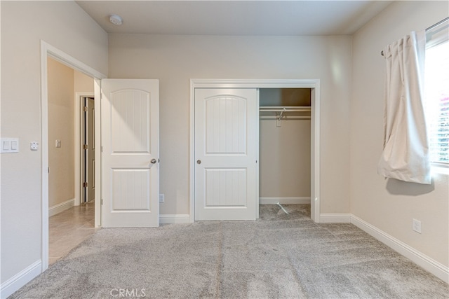 unfurnished bedroom with light carpet and a closet