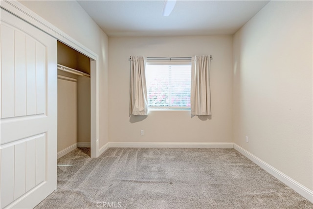 unfurnished bedroom with ceiling fan, light carpet, and a closet