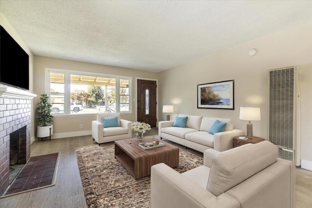 living room featuring a fireplace, light hardwood / wood-style flooring, and a textured ceiling