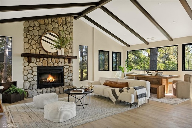 bedroom featuring light wood-type flooring, a fireplace, beam ceiling, and high vaulted ceiling