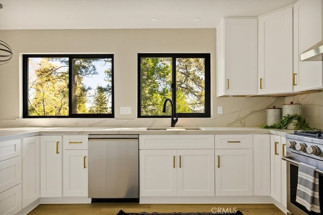 kitchen featuring stainless steel appliances, white cabinets, a wealth of natural light, and sink