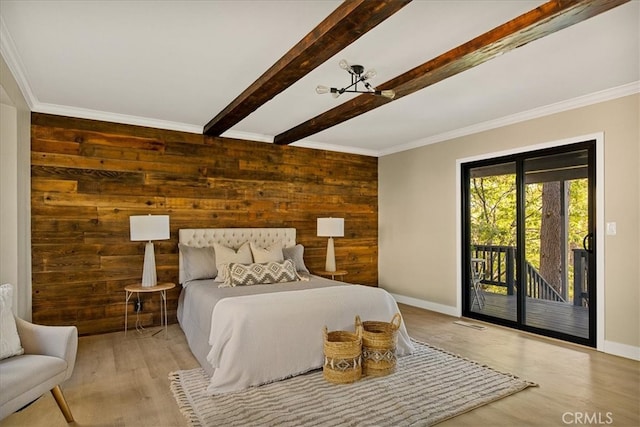 bedroom featuring beamed ceiling, wood walls, access to exterior, crown molding, and light hardwood / wood-style floors