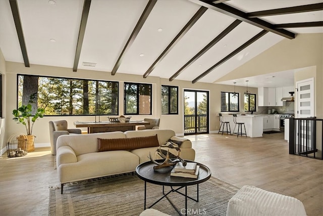 living room featuring beamed ceiling, light hardwood / wood-style flooring, and high vaulted ceiling