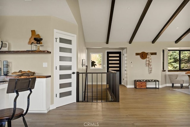 foyer entrance featuring lofted ceiling with beams, a wealth of natural light, and wood-type flooring