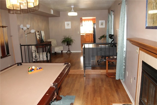 dining area with hardwood / wood-style flooring, a textured ceiling, billiards, and a fireplace