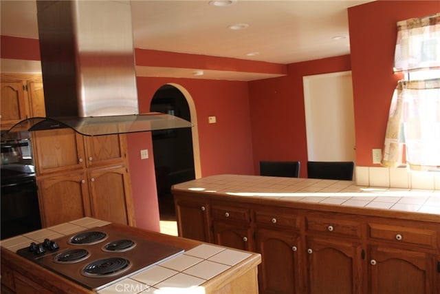 kitchen featuring stainless steel electric cooktop, tile counters, and range hood