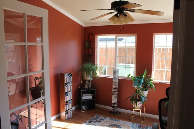 interior space with baseboards, ceiling fan, ornamental molding, and wood finished floors