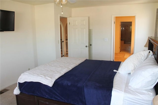 carpeted bedroom featuring arched walkways, visible vents, and connected bathroom