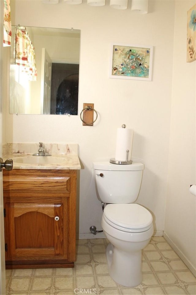 half bathroom with baseboards, toilet, and vanity
