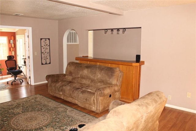 living room with a textured ceiling, baseboards, and wood finished floors