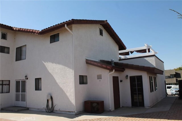 back of house with a patio, stucco siding, and a tile roof