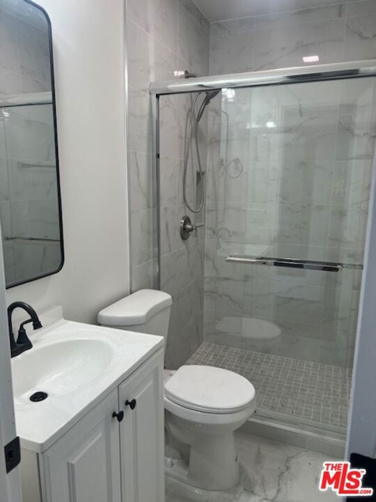 bathroom with a shower with door, vanity, and toilet