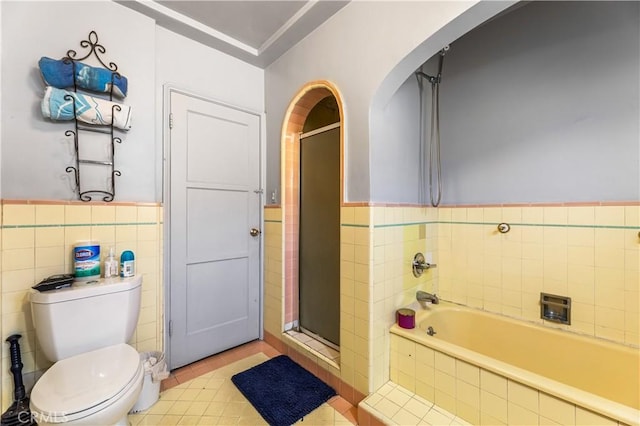 bathroom with tile patterned flooring, toilet, and tile walls