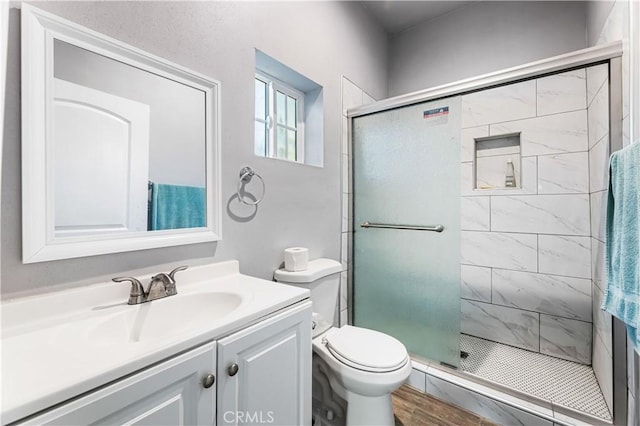 bathroom with wood-type flooring, vanity, toilet, and a shower with door