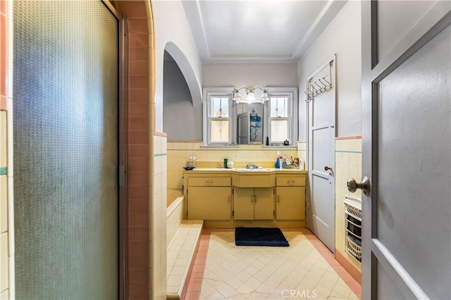 bathroom featuring tile patterned floors, vanity, a shower with shower door, and tile walls