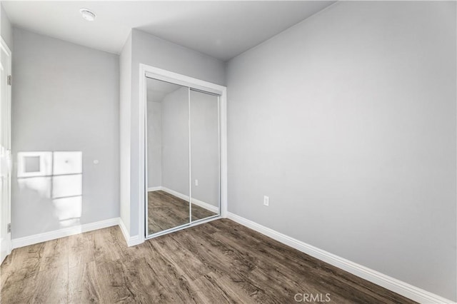 unfurnished bedroom featuring a closet and hardwood / wood-style flooring