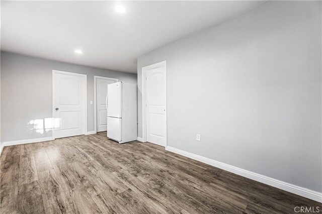 unfurnished bedroom featuring white fridge and hardwood / wood-style flooring