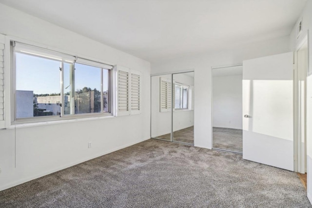 unfurnished bedroom with two closets and carpet flooring