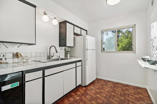 kitchen featuring white cabinets, black dishwasher, dark parquet floors, tile countertops, and sink