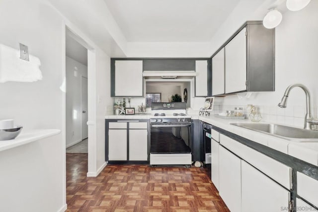 kitchen featuring white stove, sink, dark parquet floors, and white cabinets