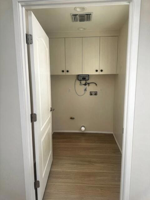 clothes washing area featuring washer hookup, cabinets, and light hardwood / wood-style flooring