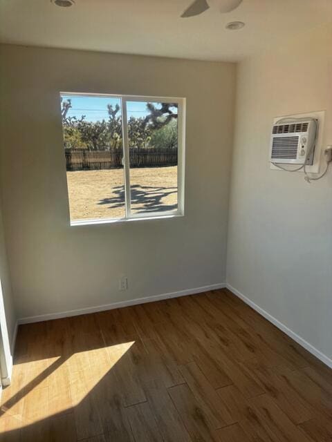 unfurnished room featuring a wall unit AC, dark hardwood / wood-style floors, and ceiling fan