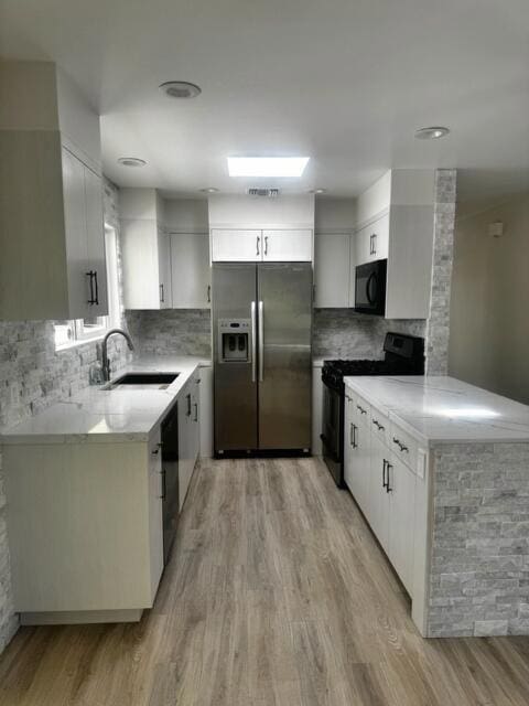 kitchen with white cabinets, black appliances, sink, and light wood-type flooring